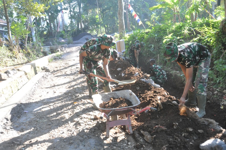 Satgas TMMD ke-129 Kodim 0821/Lumajang Optimalkan Pembangunan Drainase, Prada Muhamad Tri Dani Angkut Tanah Galian