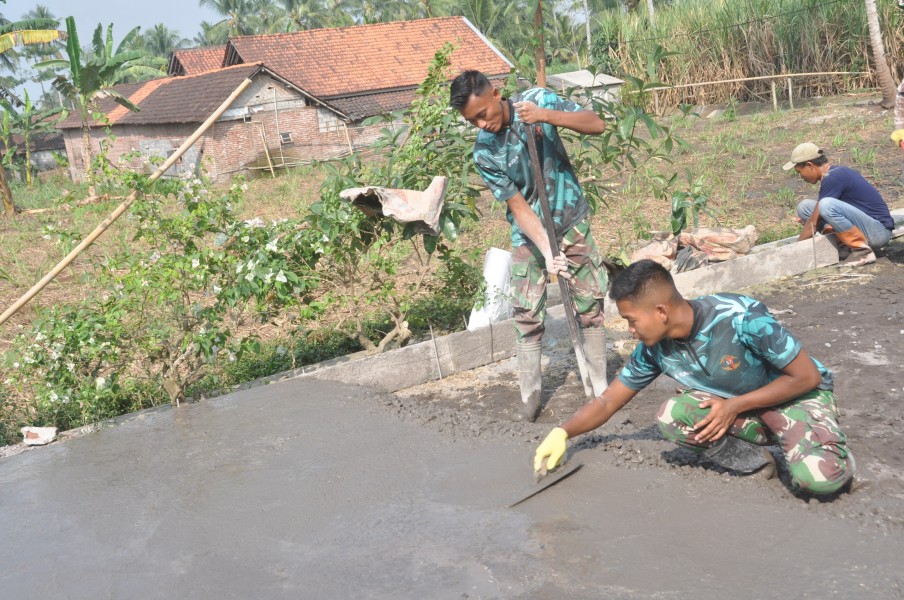 Detail Jadi Perhatian, Prada Aditya Rohman Rapikan Permukaan Rabat Beton TMMD