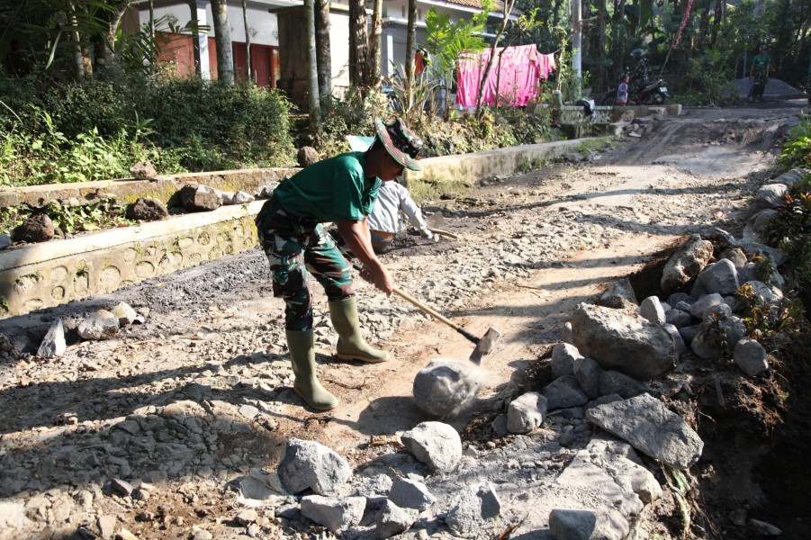 Satgas TMMD ke-129 Kodim 0821/Lumajang Maksimalkan Pembuatan Parit, Prada Muhamad Fathur Pecah Batu untuk Perkuat Drainase